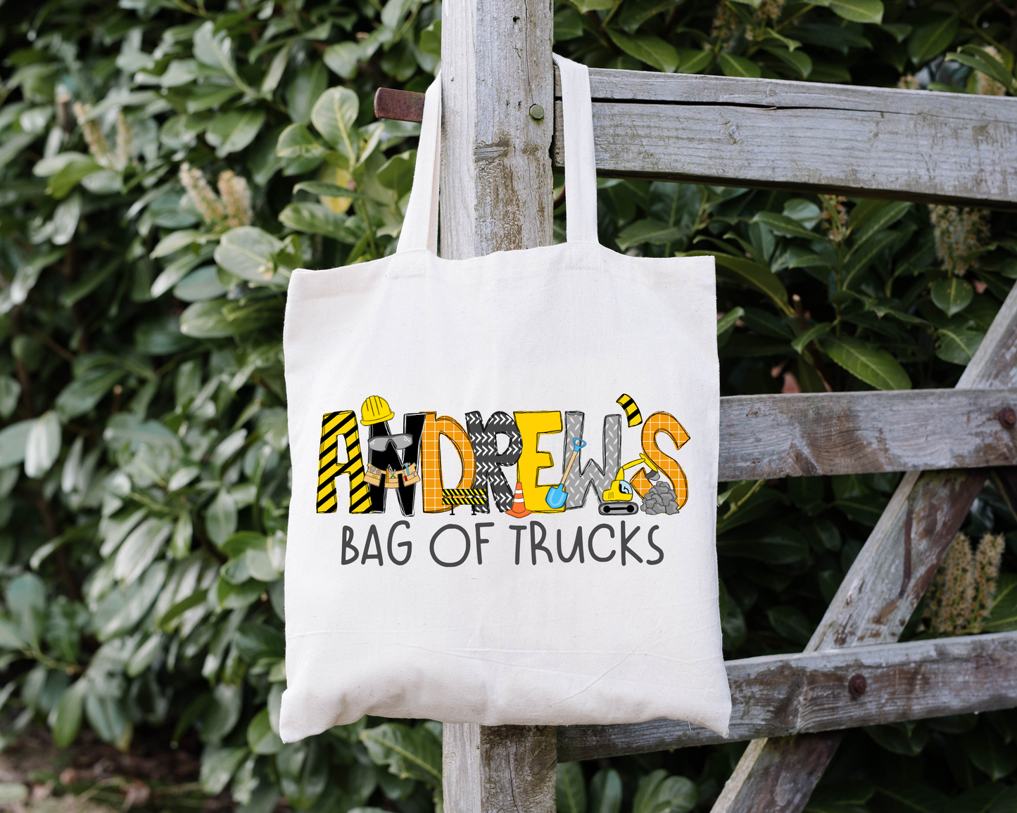 White Tote bag with Personalized Construction Themed Name and chosen phrase underneath in matching color. Perfect to use for construction toys. Personalized Construction Themed Toy Bag
